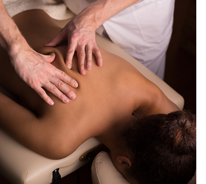 A massage therapist works on the muscles in a woman's back